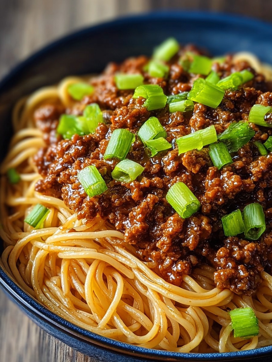 A bowl of spaghetti with meat sauce and green onions.