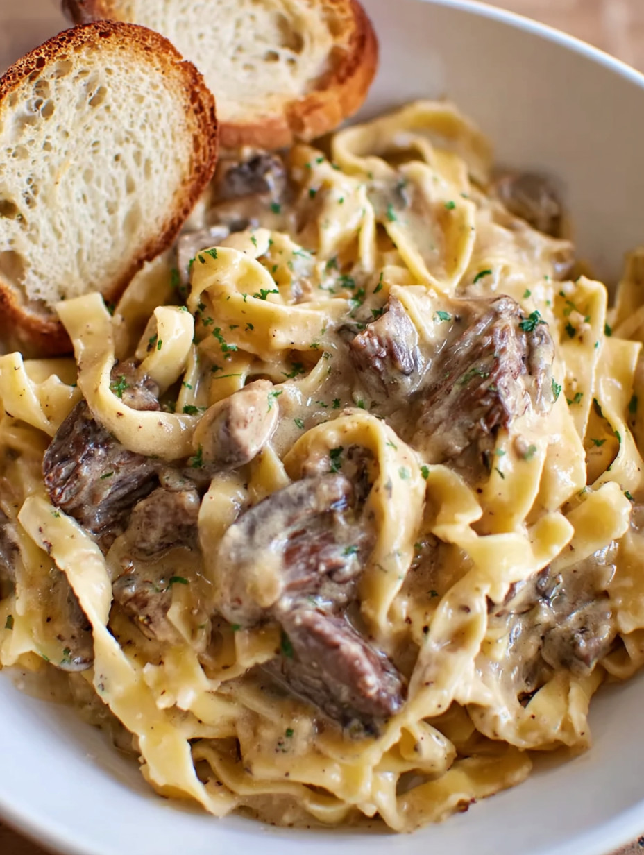A bowl of pasta with meat and mushrooms.