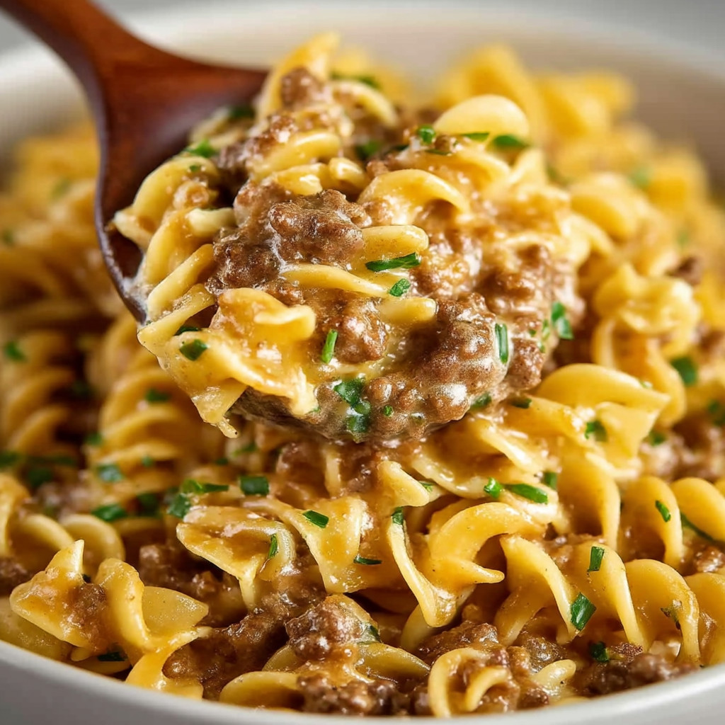 A wooden spoon is in a bowl of pasta.