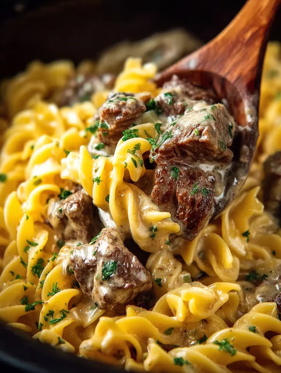 A wooden spoon in a bowl of pasta.