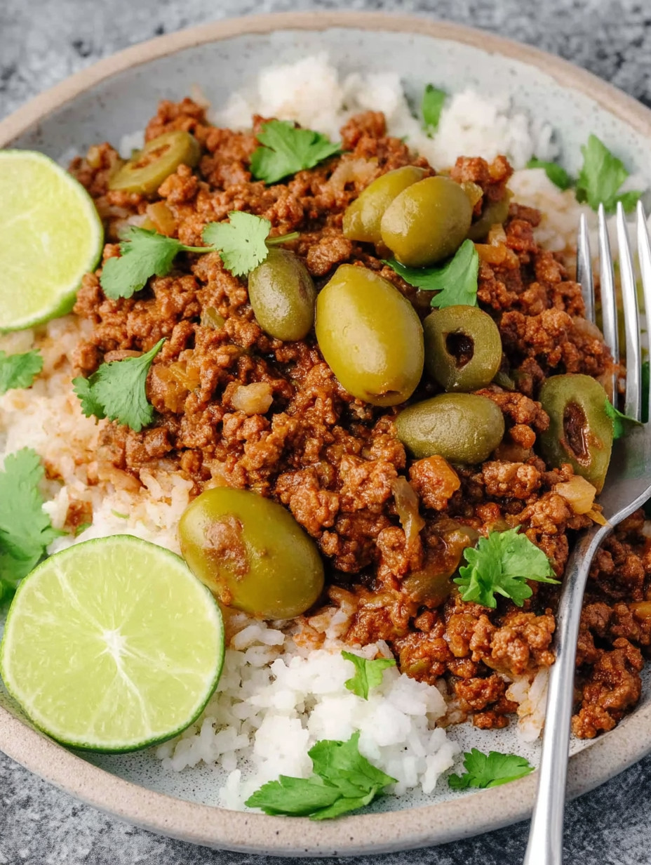 A plate of food with rice, meat, and olives.