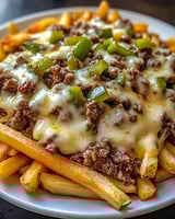 A plate of cheese fries with meat on top.