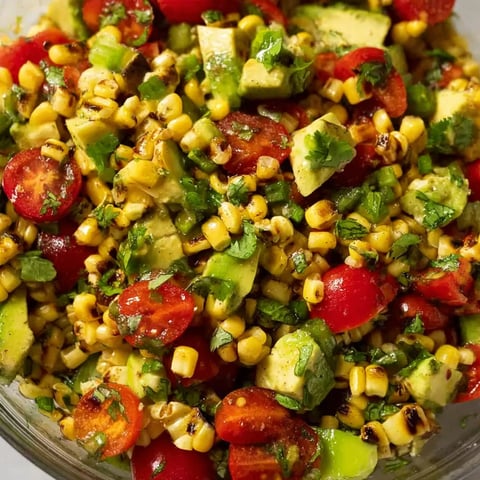 A bowl of sliced tomatoes, corn, and avocado.