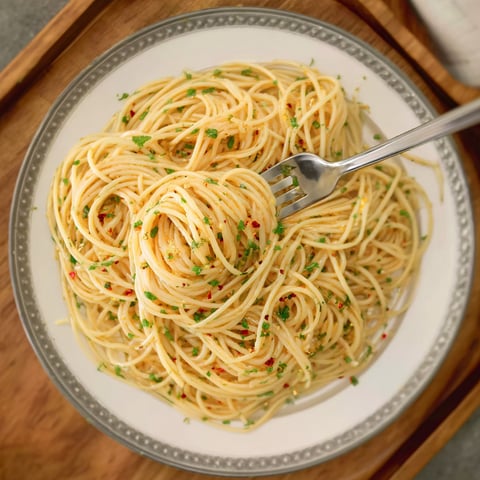 A plate of spaghetti with green herbs on top.