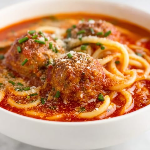 A bowl of spaghetti with meatballs and sauce.