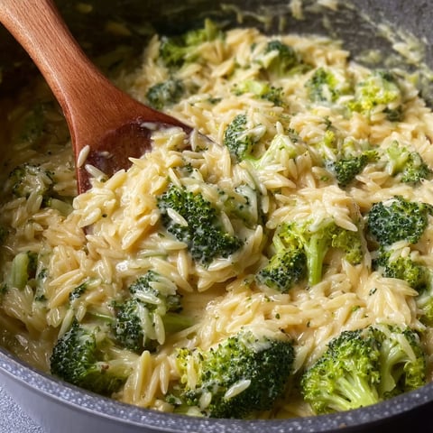 A wooden spoon in a pot of rice and broccoli.